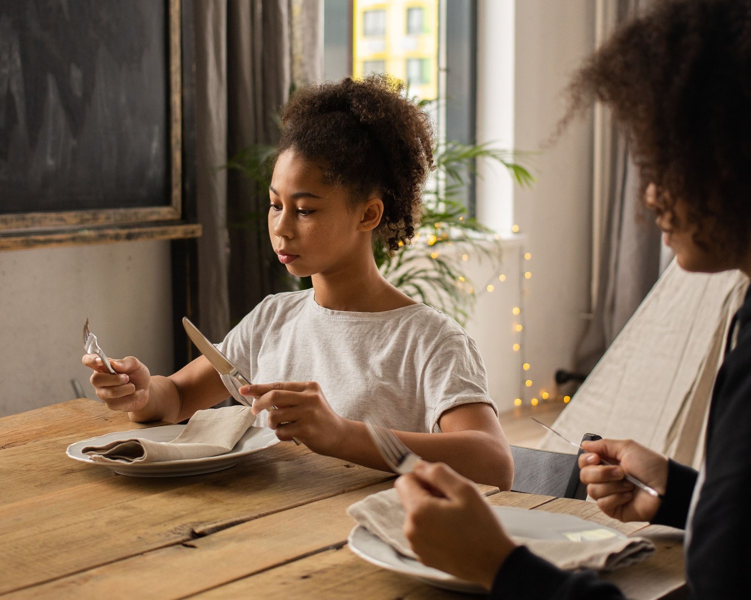 A young person learning table etiquette at a set place setting