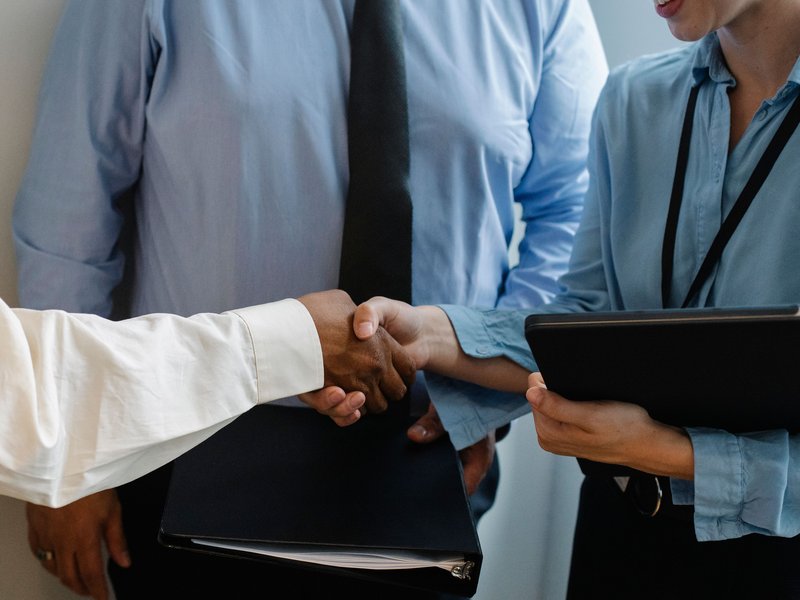 Colleagues in business dress greeting one another with a handshake